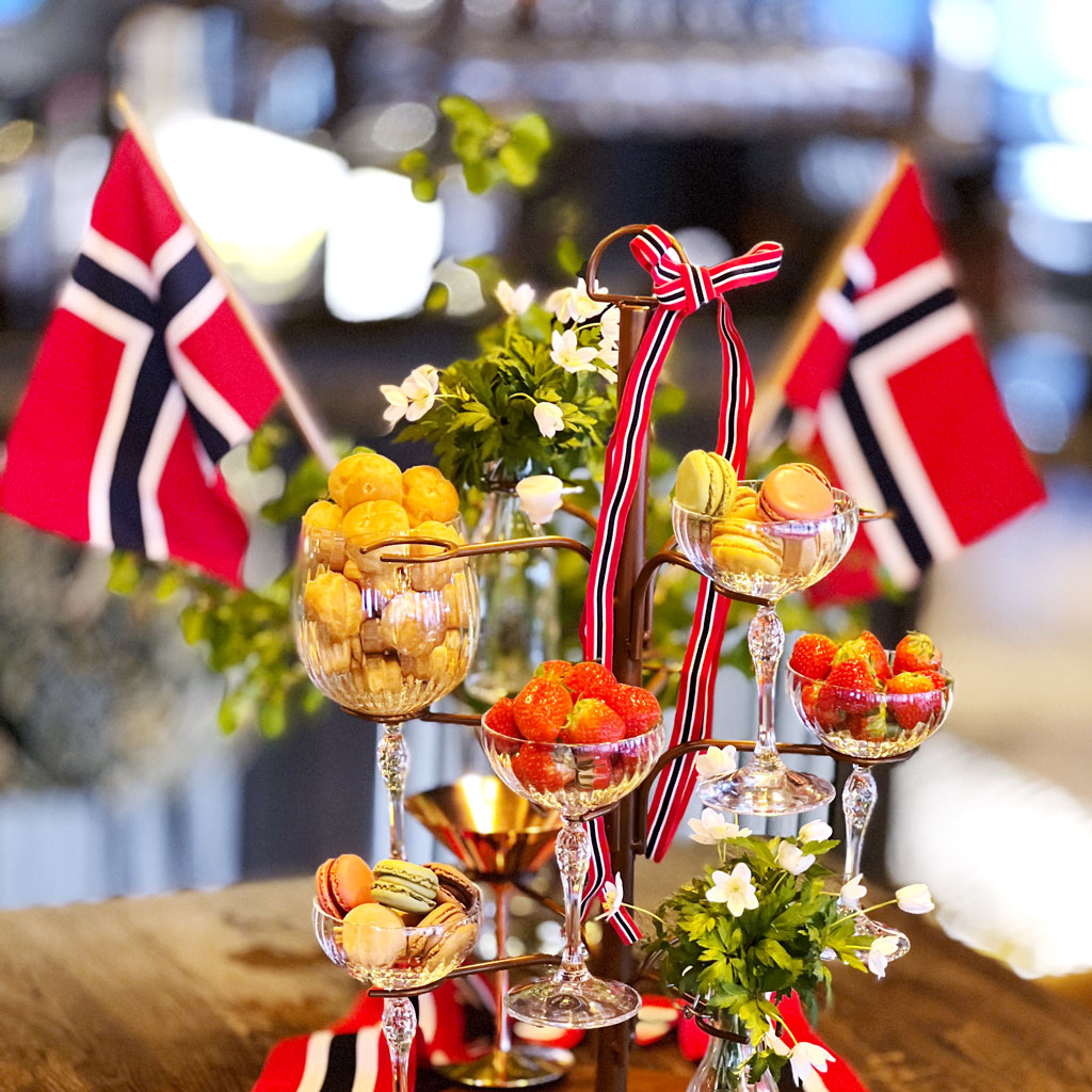 17. mai-dekor på et bord. Flagg, hvitveis, jordbær og småkaker.