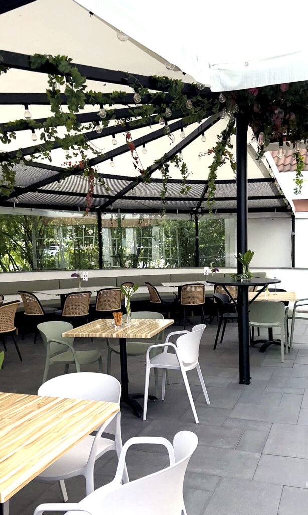 Uteserveringen utenfor Holger bar, med stoler, bord og grønne planter.