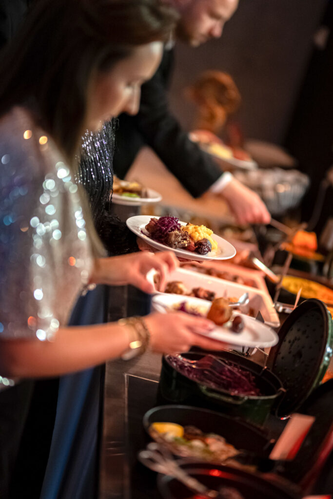 Festkledde mennesker tar julemat fra en buffet.